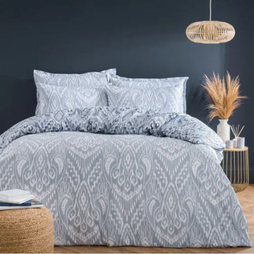 Patterned bedding set on a bed with a dark wall and decorative elements in the background.