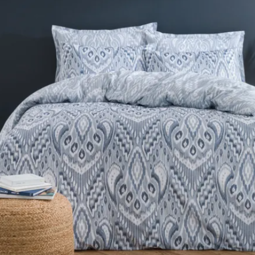 Blue patterned bedding set on a bed with a dark wall and decorative elements.
