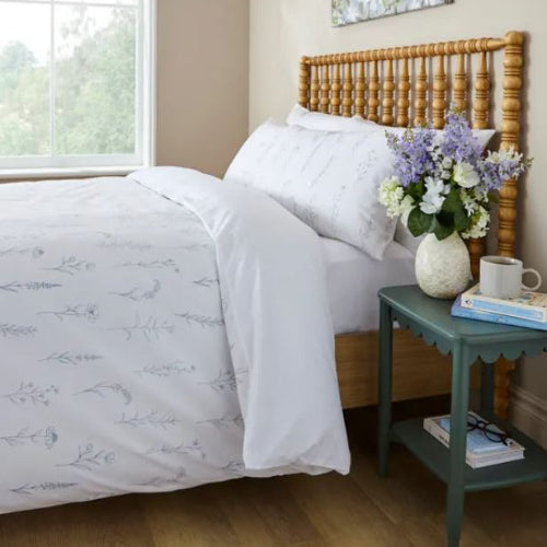 Bedroom with a wooden bed and floral arrangement on a nightstand
