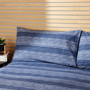 Blue striped bedding set on a bed with a wooden headboard.
